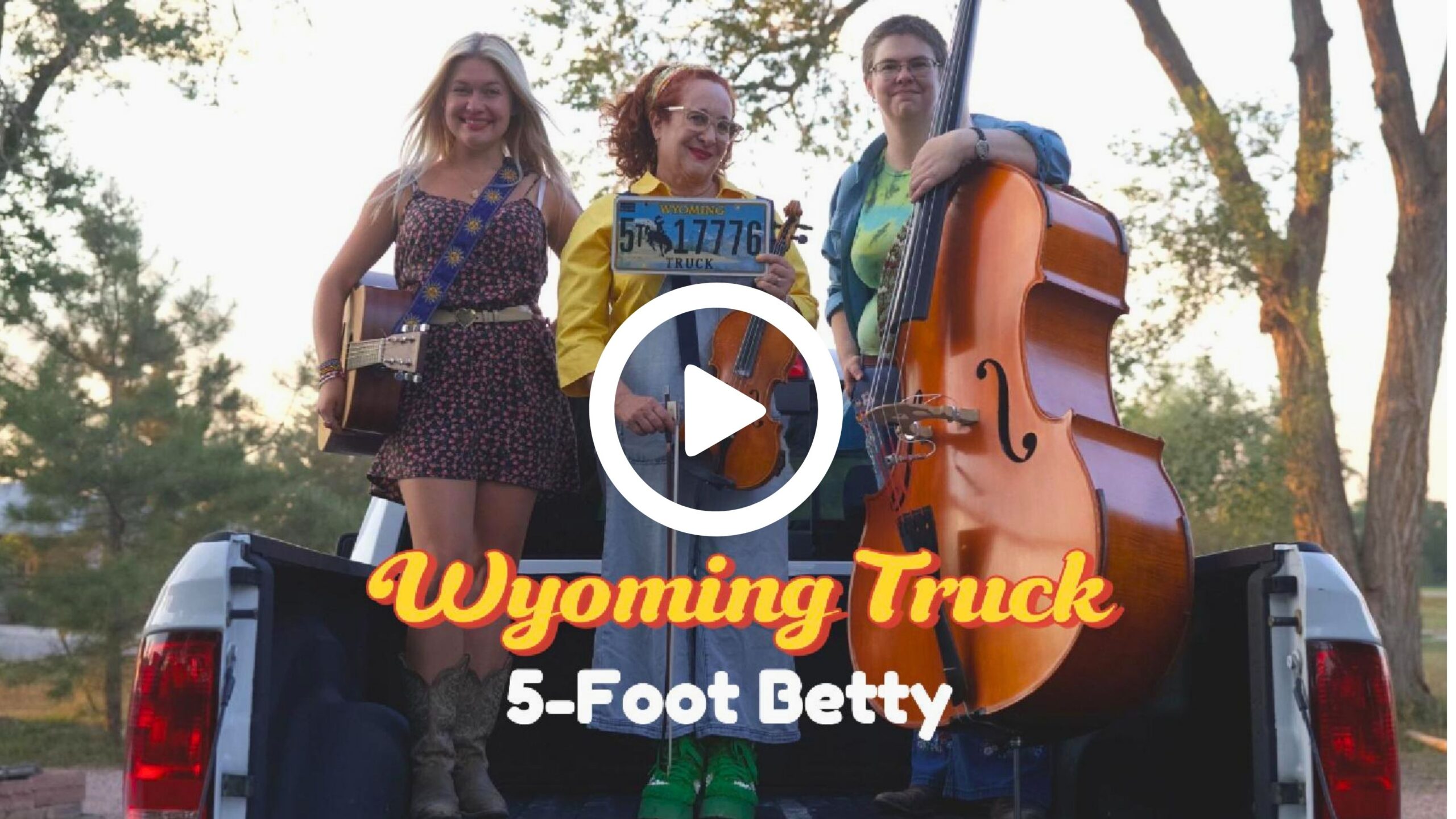 three smiling women standing in truck bed with musical instruments